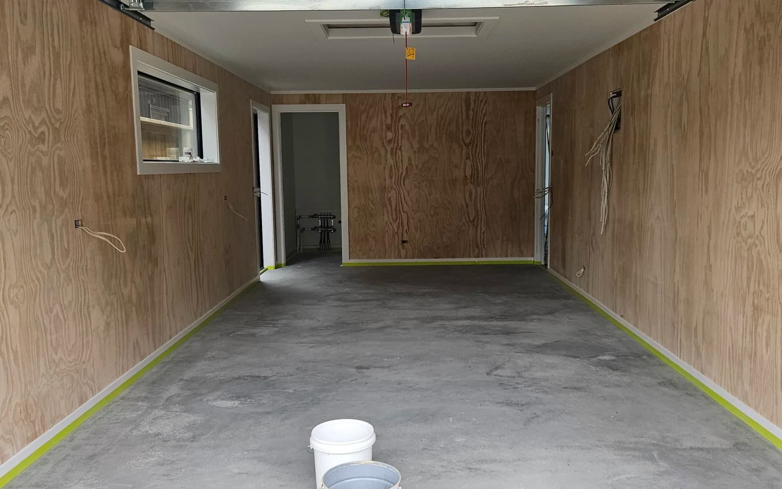 New-build garage slab masked and prepped, bare grey concrete before floor sealing, Queenstown
